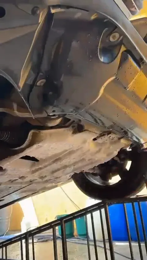 Parte inferior de um carro erguido na rampa durante a lavagem de chassi