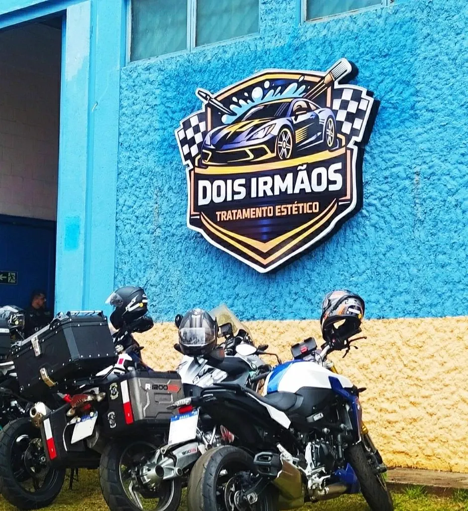 Fachada da Dois Irmãos com o logo aplicado na parede e motos estacionadas em frente
