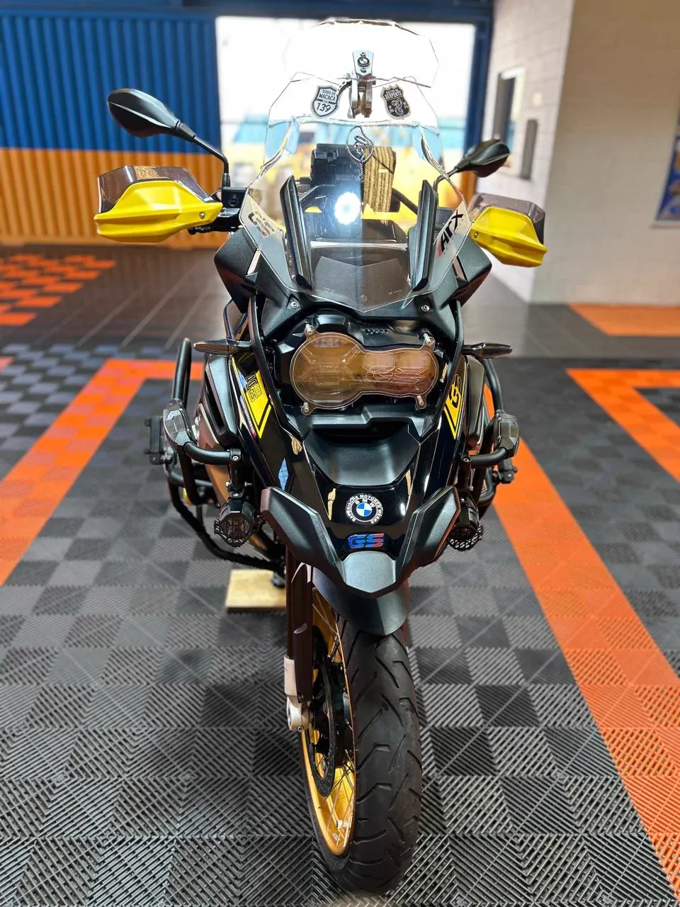 BMW GS preta e amarela no salão da Dois Irmãos, vista de frente com o farol aceso
