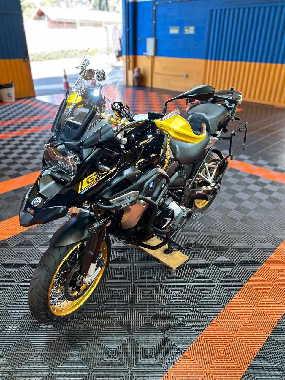 BMW GS preta e amarela no salão da Dois Irmãos, vista de lado sobre o piso quadriculado