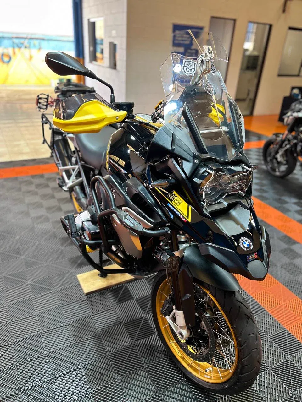 BMW GS preta e amarela no salão da Dois Irmãos, vista de frente em três quartos