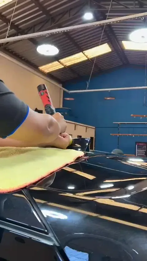 Politriz corrigindo a pintura do teto de um carro escuro