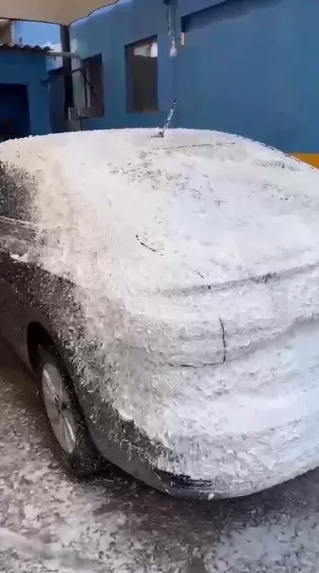 Carro coberto por espuma na área de lavagem, antes do enxágue