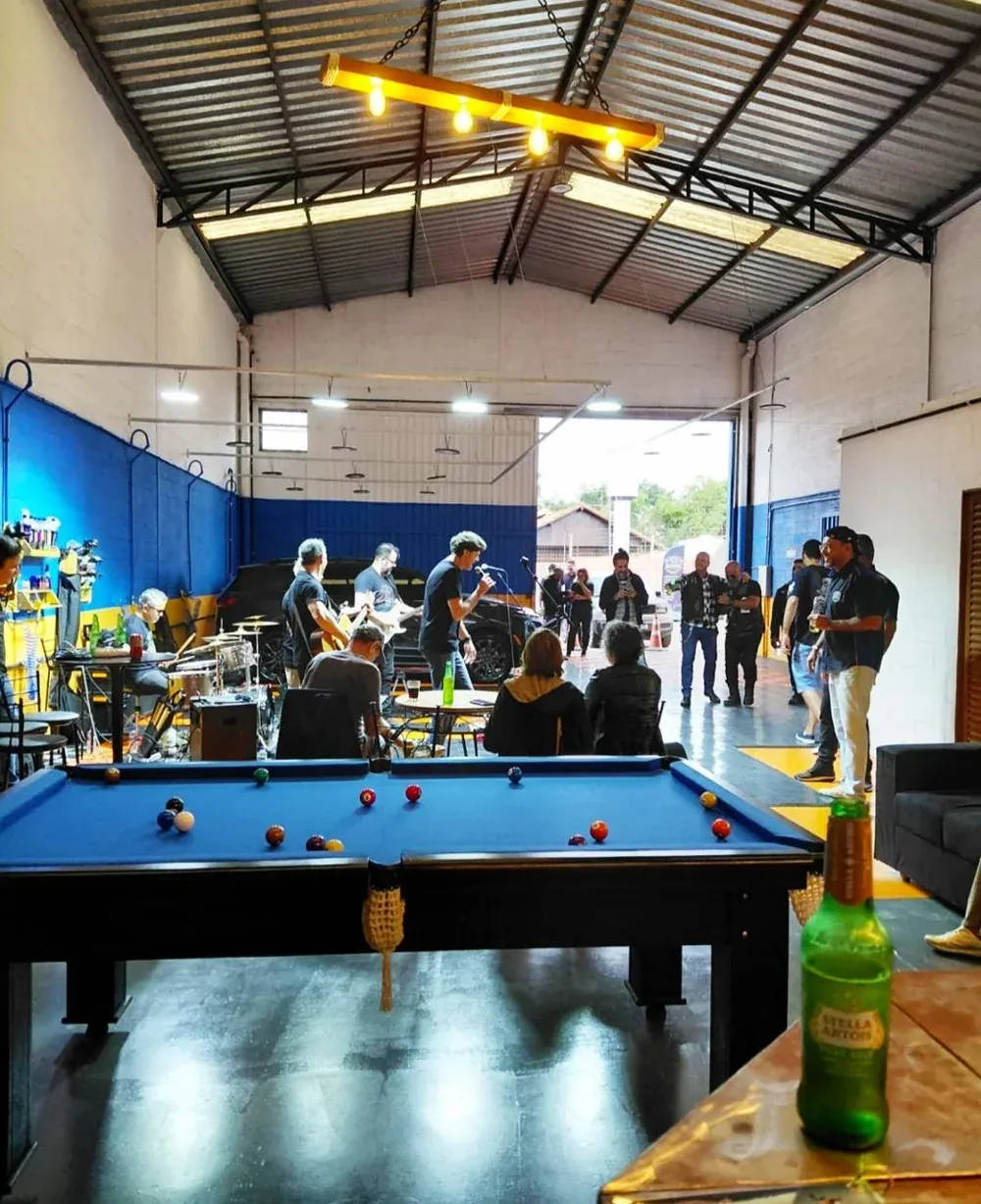 Salão da Dois Irmãos durante um evento na loja, com mesa de sinuca em primeiro plano e o galpão ao fundo