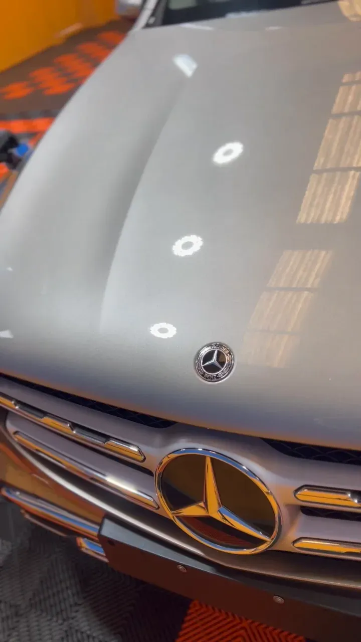 Capô de Mercedes-Benz GLC prateado refletindo as luminárias do box depois da vitrificação